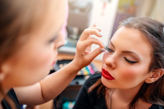 Make-up artist applying the false eyelashes to model. Close-up. 