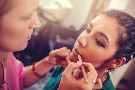 Close-up of a make-up artist contouring lips to model.  