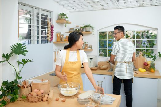 Couple cooking bakery in kitchen room, Young asian man and woman together making cake and bread with egg,