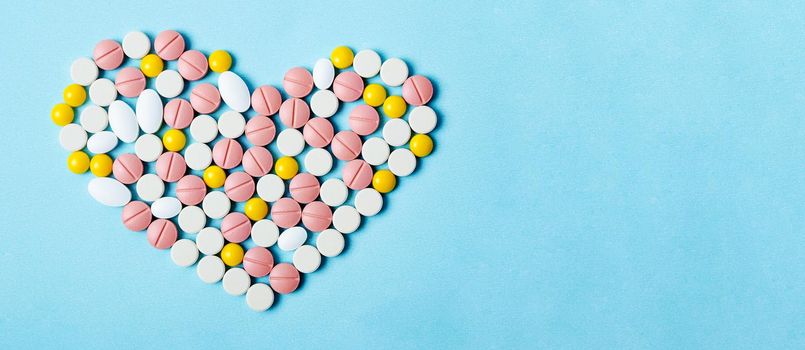 Many colorful pills macro on blue background.