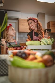 Happy mother and her daughter enjoy making and having healthy meal together at their home kitchen.