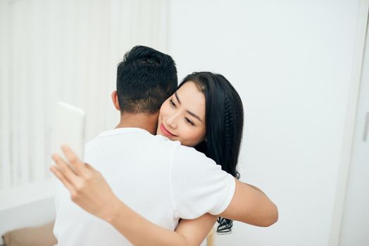 Young couple in the bedroom. An attractive woman is checking incoming messages in the morning