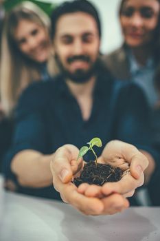 University colleague biologists is holding a young plant in soil in hands and checking the quality of the sample.