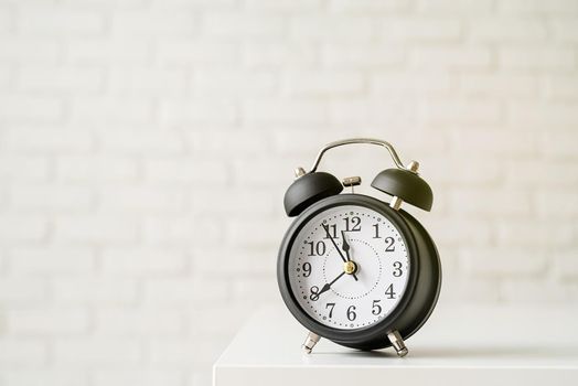 Time management, punctuality, business metaphors. Black vintage alarm clock with twenty to nine on white brick wall background, copy space