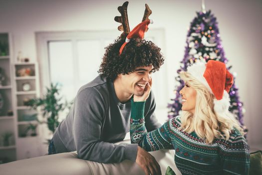 Loving couple in cozy warm sweaters on a Christmas - New Year eve, smiling and having fun with each other. 