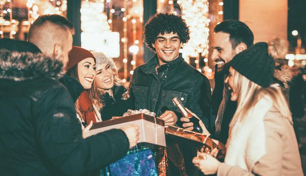 Six beautiful young people having fun while buying some presents and smiling holding many shopping paper bags and boxes in town street.