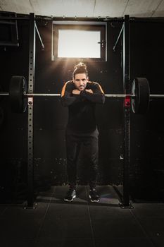 Young muscular man ready to do hard exercise with barbell on cross training at the gym.