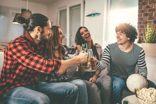 Friends are fans of sports games as football love spending their free time at home together. They are screaming and gesturing for a victory. 