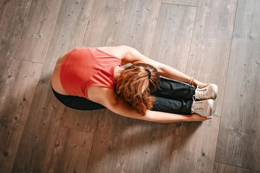 Above view of a woman doing stretching exercises on floor.