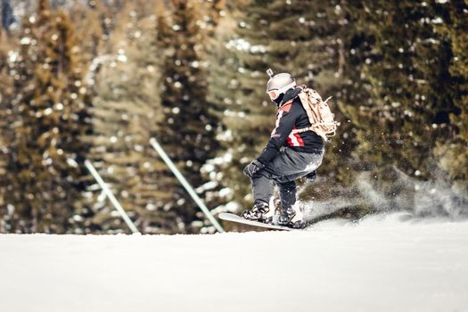 Young man rides snowboard and enjoying a frozen winter day on mountain slopes.