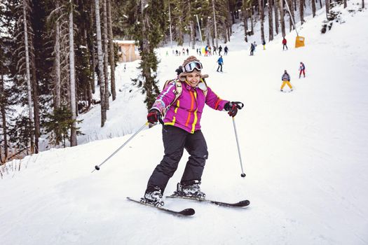 Little girl is skiing, on the mountain, and enjoying in nice snow day.