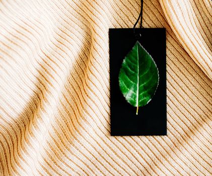 Natural fabric and green leaf on price tag as eco-friendly flatlay background, sustainable fashion and brand label concept.