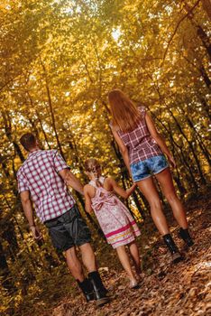 Rear view of a beautiful young family enjoying a walk in the forest.