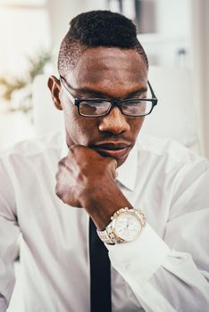 A portrait of a pensive African businessman, who is working in modern office.