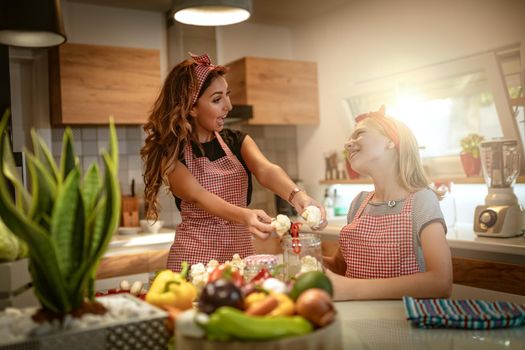 Happy mother and her daughter enjoy preparing for marinating cauliflower and making healthy meal together at their home kitchen.  