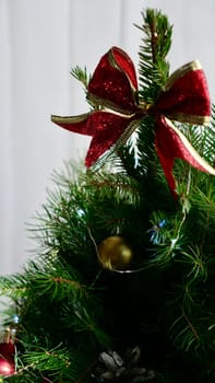 A festive red bow on a green Christmas tree , white background of Christmas lanterns on New Year's Eve.