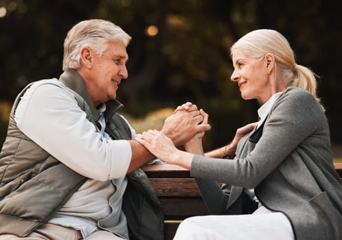 Love, park bench and senior happy couple holding hands, bond and enjoy time together, freedom and connect in garden. Eye contact, trust and support of old man, woman or marriage people on nature date.