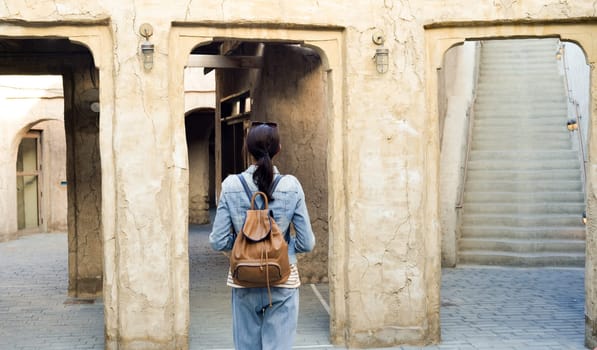 A young woman traveler walks enjoying the old narrow streets of Dubai Deira and Creek. Travel and sightseeing concept