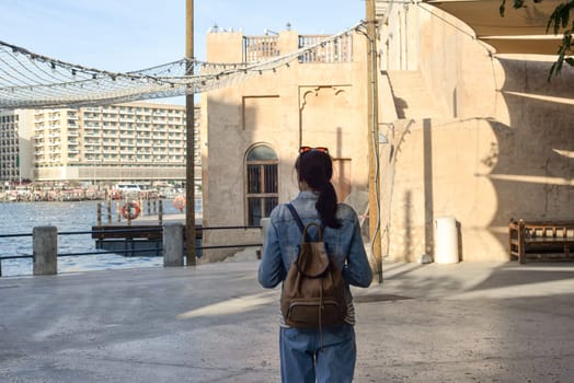 A young woman traveler walks enjoying the old narrow streets of Dubai Deira and Creek. Travel and sightseeing concept