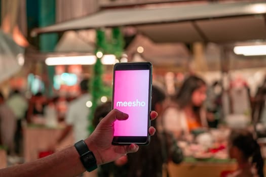 Delhi, India - 2nd Apr'23 : woman holding mobile phone showing indian social commerce startup Meesho logo at an event