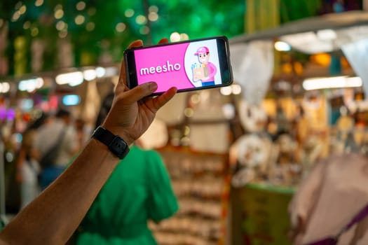 Delhi, India - 2nd Apr'23 : woman holding mobile phone showing indian social commerce startup Meesho logo at an event