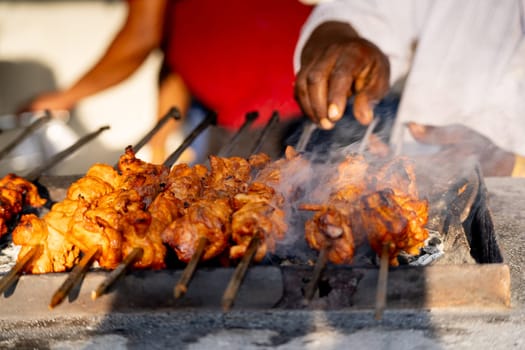 smoking kebab tikka shot with heat haze, smoke coming and butter marinade dripping while a chef cook works in the background showing chicken, mutton food