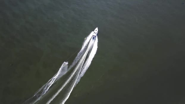 A young man is skiing. A sports guy is skiing on the water behind a boat. Top view from a drone. 4k