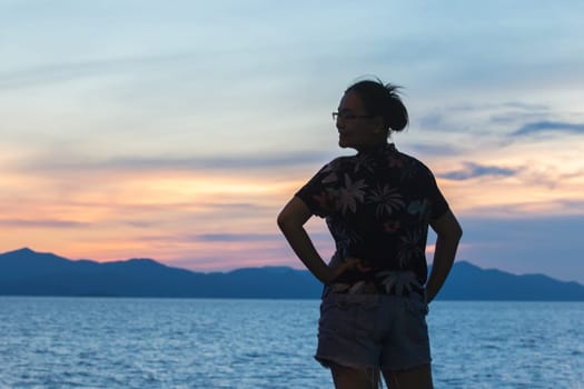 Silhouette of a woman standing and watching the sunset