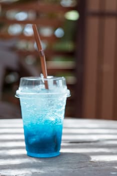 Blue soda in a plastic glass placed on a wooden table