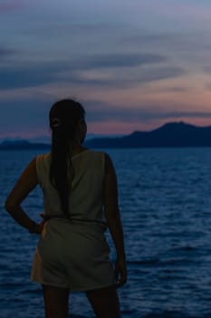 Silhouette of a woman standing with the sunset in the beautiful sea