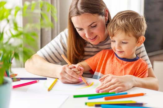 Happy family concept. Mother and her son drawing together. An adult woman helps a boy paint.