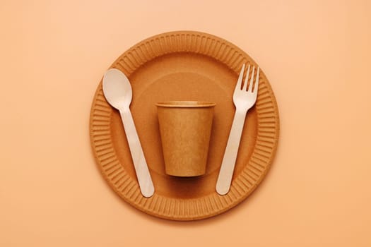A set of disposable tableware on a brown background. Eco-friendly utensils for eco-friendly parties or picnics