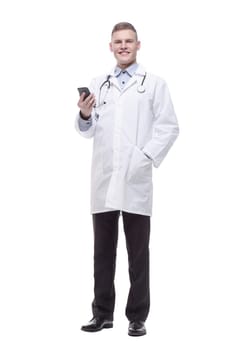 in full growth. young doctor with a smartphone. isolated on a white background.