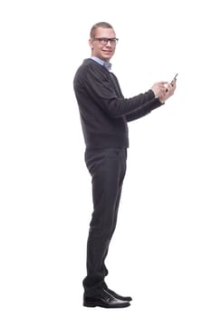 casual young man is pointing to his side while speaking on the phone and smiling to the camera standing on white background