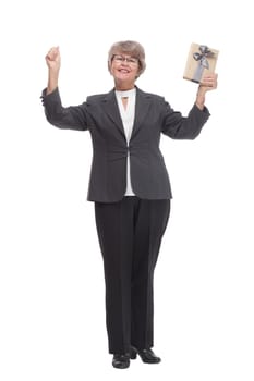 Full body senior woman happy and smiling, holding a gift and pointed on it looking at camera
