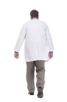 in full growth. serious doctor in a white coat striding forward.isolated on a white background.