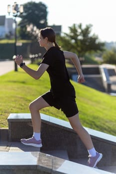 A young woman in black clothes running on stairs at city street early morning.