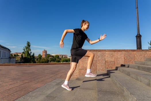 A young woman in black clothes running on stairs at city street early morning.