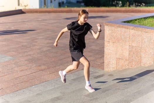 A young woman in black clothes running on stairs at city street early morning.