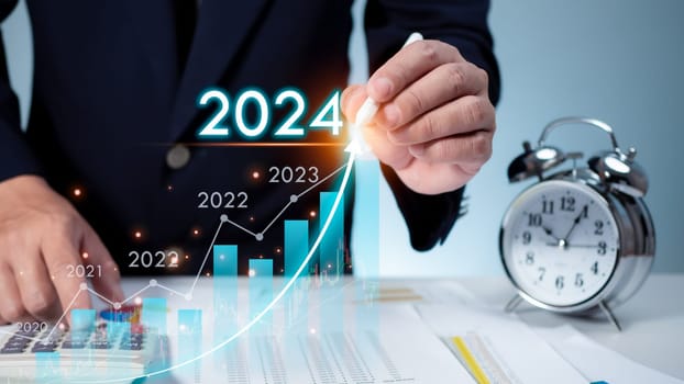 Stock trading. Finance. Investing. Growing business. Businessman in suit pointing with a pen at the tip of an arrow and a graph bar Represents business growth in 2024.