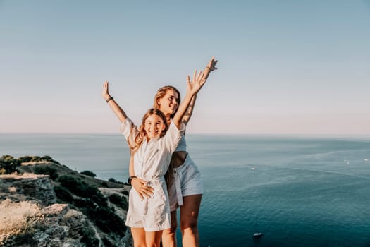 Close up portrait of mom and her teenage daughter hugging and smiling together over sunset sea view. Beautiful woman relaxing with her child.