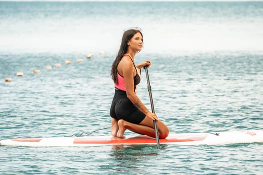 Close up shot of beautiful young caucasian woman with black hair and freckles looking at camera and smiling. Cute woman portrait in a pink bikini posing on a volcanic rock high above the sea