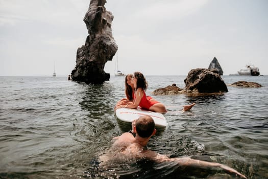 Woman sup yoga. Middle age sporty woman practising yoga pilates on paddle sup surfboard. Female stretching doing workout on sea water. Modern individual hipster outdoor summer sport activity