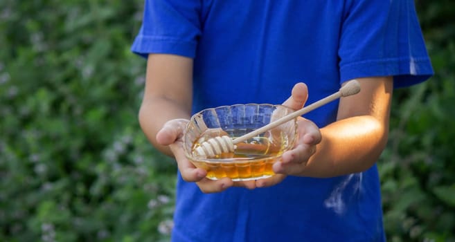 the boy eats honey in the garden, honey from his apiary. Selective focus. Nature