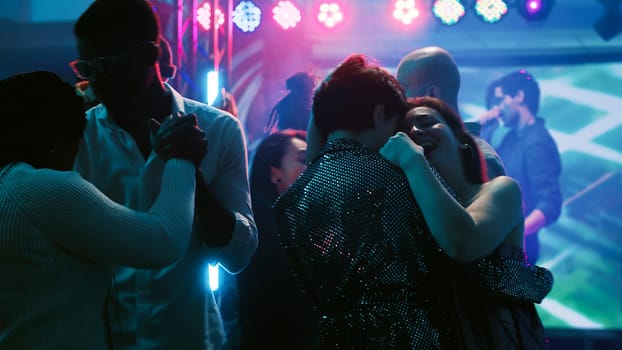 Dance partners waltzing on dance floor, attending party with friends at discotheque. Young people dancing in pairs on slow romantic music, showing off dance moves at club. Tripod shot.