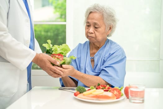 Asian elderly woman patient eating salmon steak breakfast with vegetable healthy food in hospital.