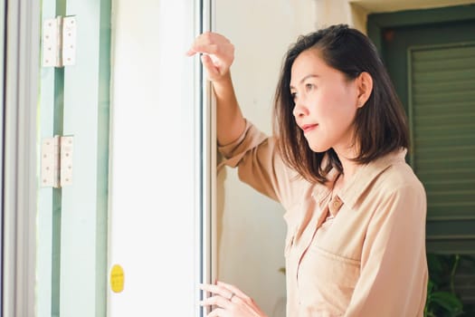 Women are standing against the wall with old wooden windows.