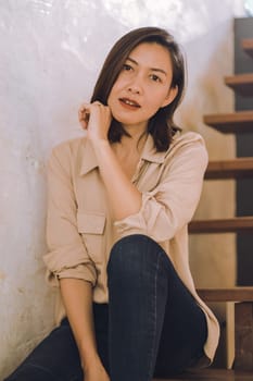 A woman sitting at an old wooden staircase