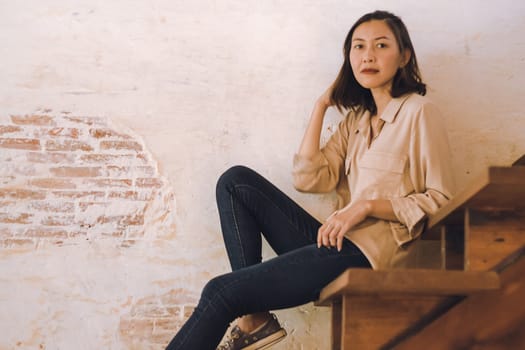 A woman sitting at an old wooden staircase