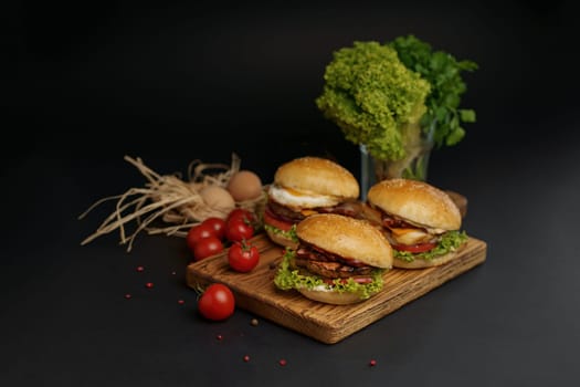 Homemade tasty double burger with beef, salad, bacon, tomatoes and cheese on wooden background. Rustic style.